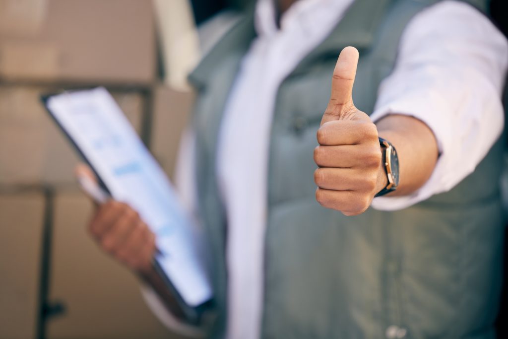 Fast delivery is our promise. Shot of a delivery man showing thumbs up and holding a clipboard.